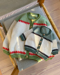 Cross Cardigan Junior og Cross Cardigan Baby liggende sammen på en stol