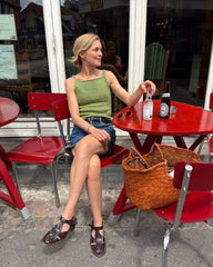 Kvinde iført grøn Emmy Top siddende ved cafébord