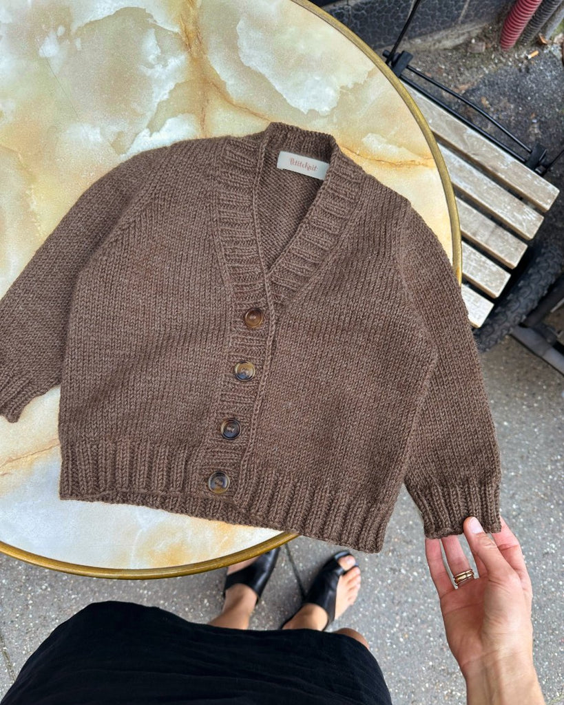 Brun Eva Cardigan Junior liggende på cafébord
