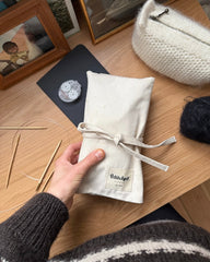 Knitter's Needle Case pindeetui til rundpinde lukket på bord med strikkepinde og omgangsgtæller