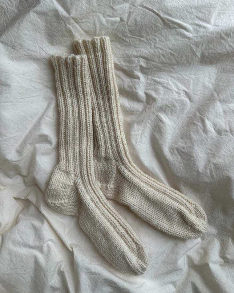 Lyserøde Sunday Socks Junior på dyne